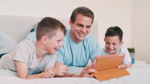 Father and Sons Relaxing with Tablet on Bed