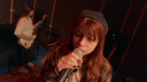 Portrait of Young Woman Singing into Microphone in Punk Rock Band in Studio