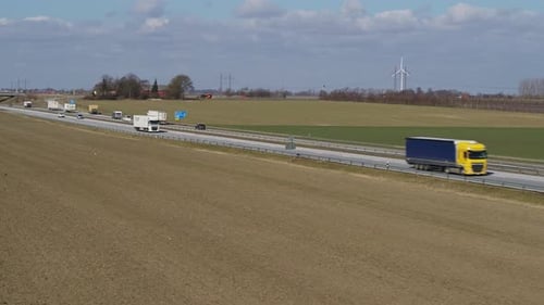 Drohnen fliegen im Frühjahr über ein Feld neben einer Autobahn mit Verkehr