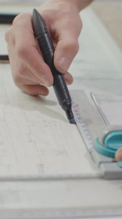 Detalhe do desenho técnico preciso e do processo de medição com a mão usando a caneta e a ferramenta de corte
