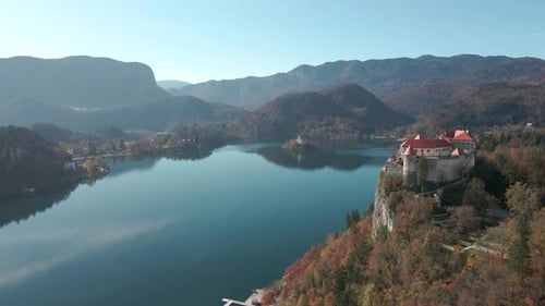 Aerial view of Lake Bled castle with the drone flying towards and past the castle with the lake and