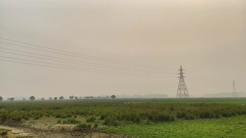 High-voltage power lines stretch along Bangladesh rural landscape, pan left view