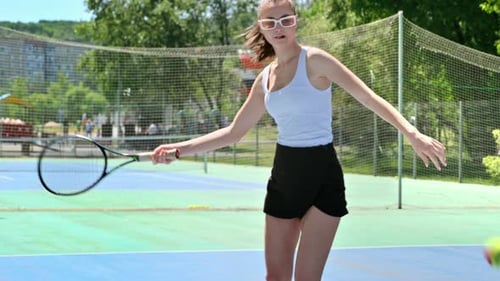 Woman playing tennis on a blue and green court on a sunny day
