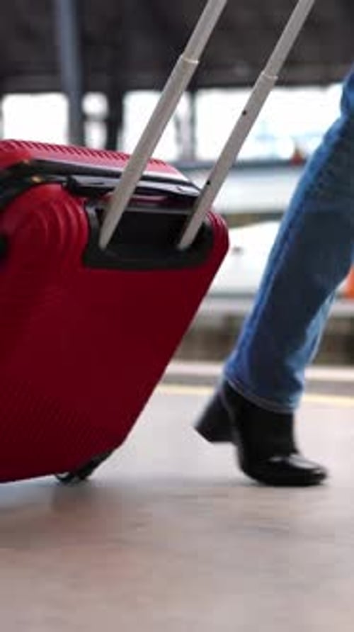 Closeup View of Young Woman Pulling Luggage at Train Station