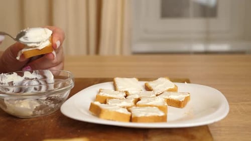 Woman Spreading Cream Cheese on Toast in Kitchen