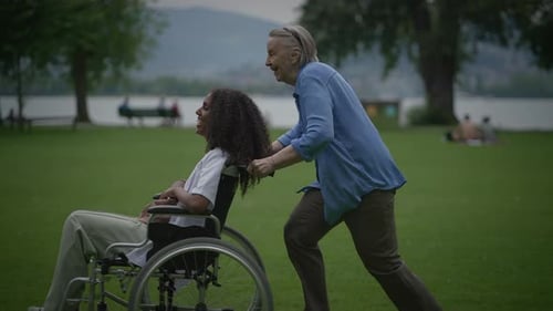 Woman in Wheelchair Pushed Through Park by Senior
