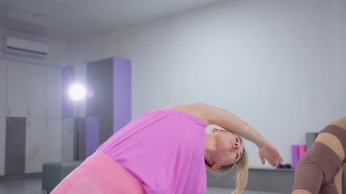 Women Stretching and Exercising in Gym with Light Reflection on Mirror