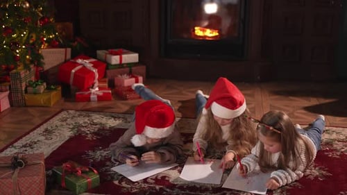 Children Drawing Christmas Pictures by Cozy Fireplace