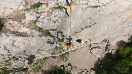 Climber rappelling down cliff with helmet and backpack