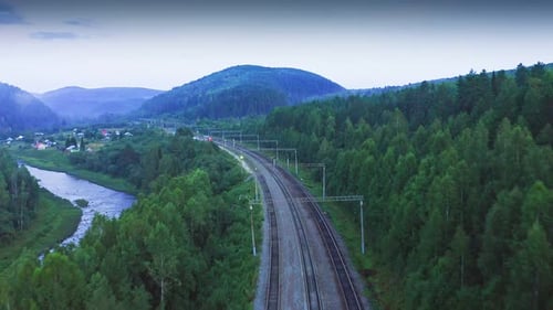 Vista aérea da ferrovia entre florestas verdes e montanhas