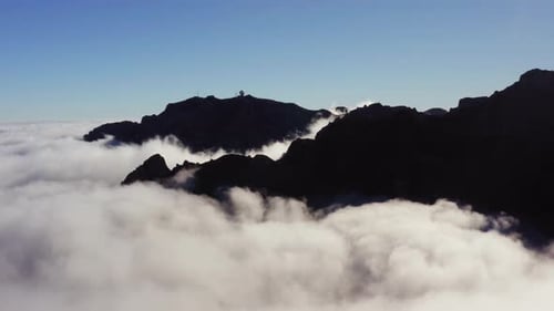 Aerial view overlooking mountain peaks and clouds, in Madeira - tracking, drone shot