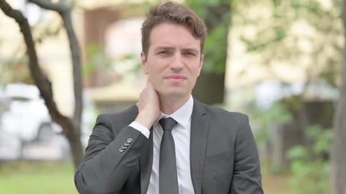 Man in Suit Rubbing Stiff Neck Outside