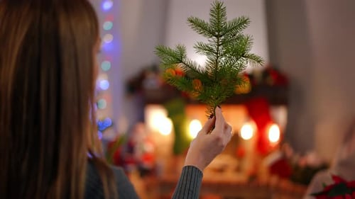 Woman Arranging Decorative Christmas Evergreen Trees at Home