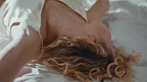Woman Relaxing in Bed with Silk Pajamas
