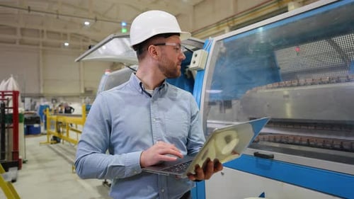 Industrieller Programmierer überprüft das Förderband mit einem Laptop