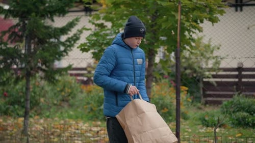 Boy Dumping Brown Paper Bag of Fall Leaves