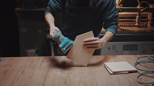 Closeup of a Woodworker's Hand Sanding Wood Details with a Grinder in His Workshop Cinematic Effect