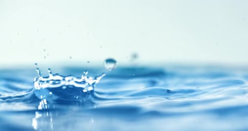 Blue Water Droplets Splashing on Rippled Surface