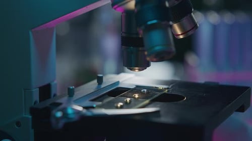 Close Up of Analyzing Specimen on Illuminated Slide under Microscope