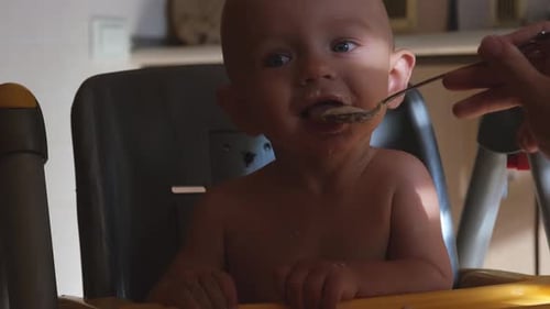 Joyful Baby Eats Meal with Spoon