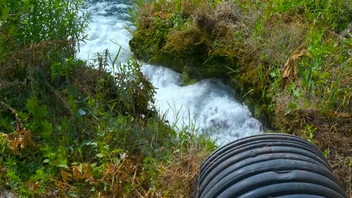 Water Flowing From a Pipe Into a Stream
