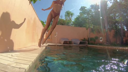 Young Happy Woman Jumping Underwater and Diving in a Blue Swimming Pool Making Water Bubbles and