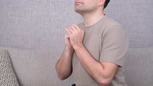 Man Praying with Hands Clasped on Couch