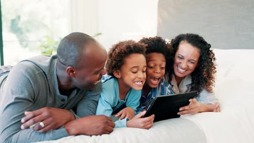 Family of Four Laughing While Looking at Tablet