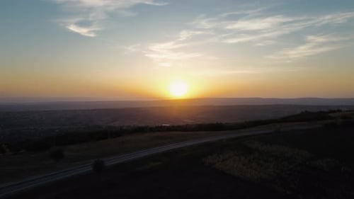 Road on the crest of a hill filmed with a drone at sunset.