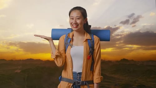 Asian Female Hiker Smiling And Pointing To Side On The Top Of Mountain
