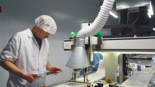 Un technicien ajuste les paramètres du robot à souder L'opérateur utilise une tablette pour calibrer l'équipement de soudage