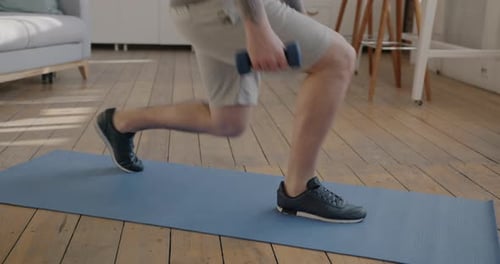 Man Doing Lunges with Dumbbell on Yoga Mat