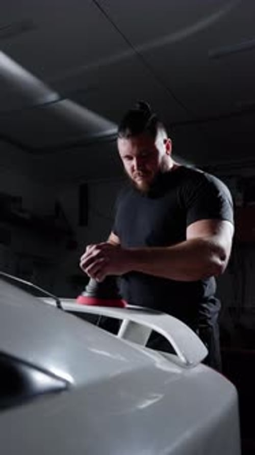 Man Polishing Car with Power Buffer in Garage