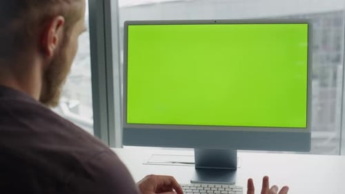 Man videocalling chromakey computer at modern office green screen room