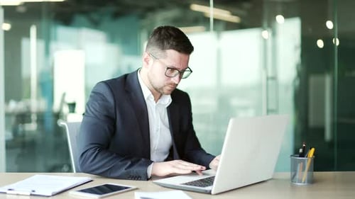 Frustrated businessman in a formal suit having problems with software or service on laptop computer