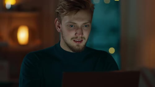 Evening at Home: Portrait of Handsome Man Sitting at His Desk Working on a Laptop. Smiling Freelanc