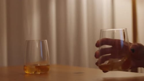 Woman Drinks Whiskey in Softly Lit Room at Night