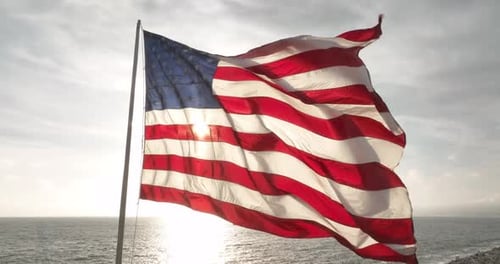 American Flag Waves Near the Ocean at Sunrise