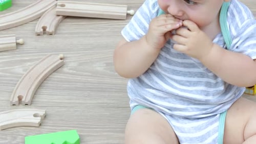 Baby Plays with Toy Blocks on Wooden Floor