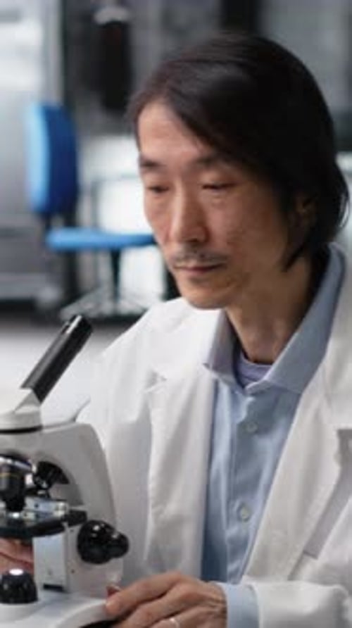 Man Works With Microscope in Laboratory Setting