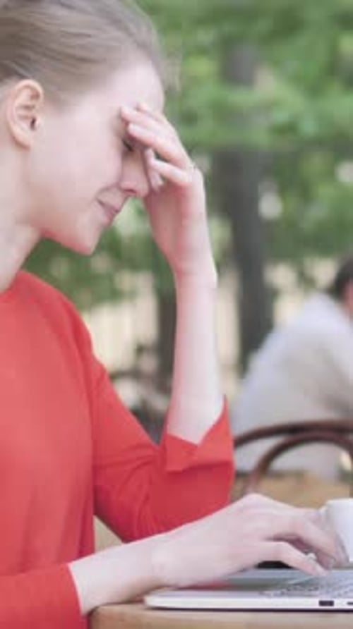 Young Woman with Headache Using Laptop Sitting in Cafe Terrace, Vertical Video