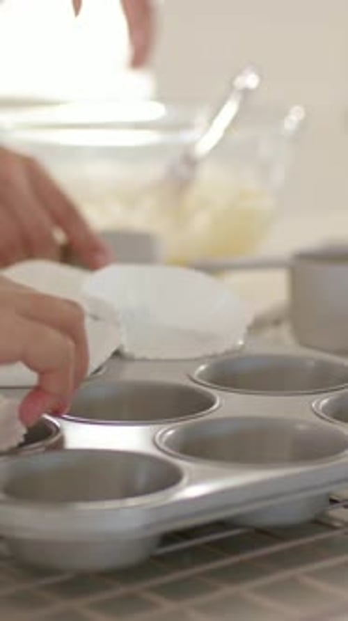Vertical video: Picking up liner, hands placing liners into metal tin for batter at home, blue top