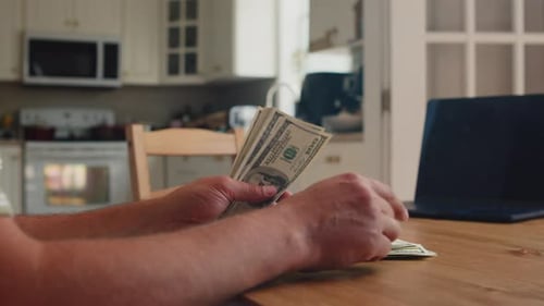 Financial Moment At Home As Man Counts Hundred Dollar Notes On Table