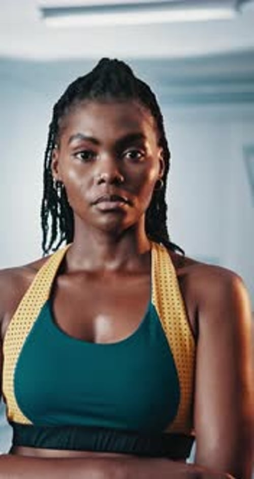 Mujer negra, cara y brazos cruzados en el gimnasio para entrenar, fortalecer o desarrollar músculos para estar en forma
