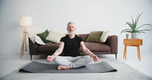 Man Practices Yoga Meditation in Bright, Simple Room