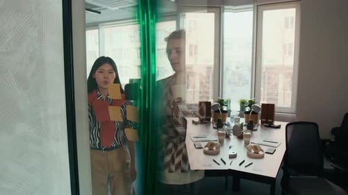 Team Brainstorms Ideas Using Sticky Notes on Glass