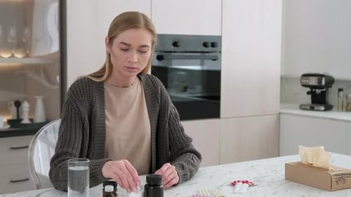 Young Woman Taking Pills at Kitchen Table