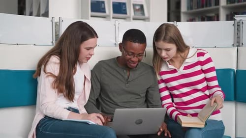 Groupmates Look at Laptop Monitor in Library
