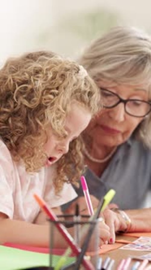 Child Drawing with Senior Woman at Table Indoors
