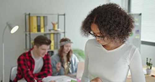 Hermosa joven afroamericana con cabello rizado sonriendo mira a la cámara sosteniendo un papel